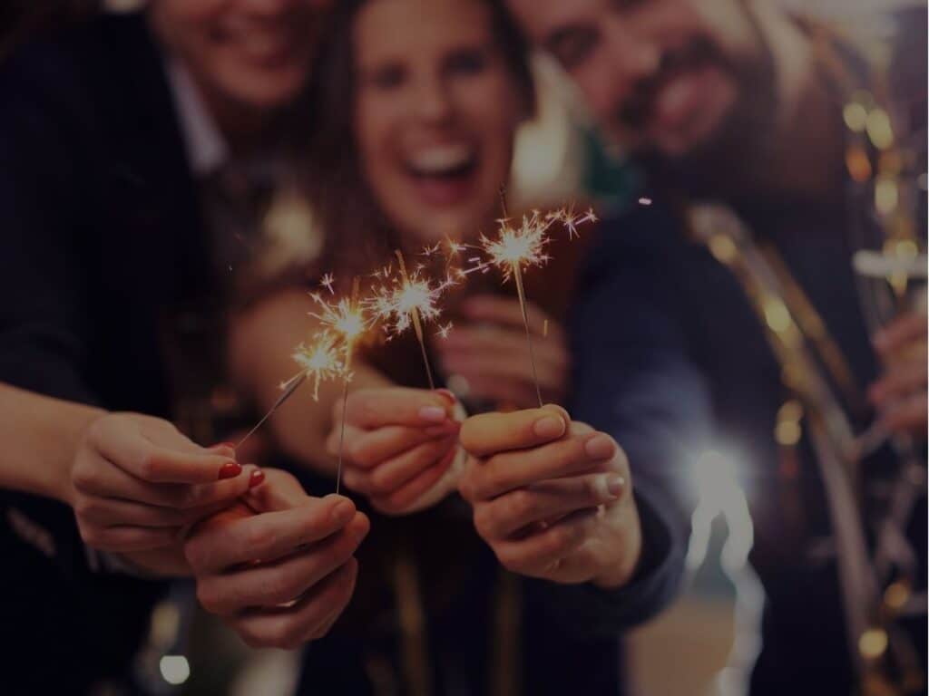 Group of friends holding sparklers, celebrating with joy and festive energy.