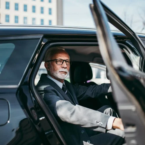 Man in a suit inside of a black car
